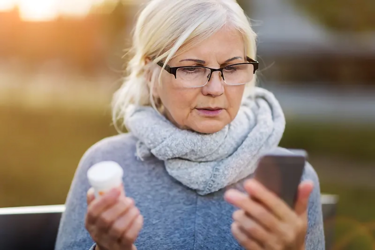 woman holding medication and phone